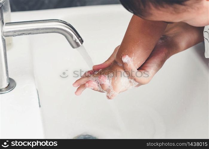 Mother wash baby hand for prevention of novel Coronavirus Disease 2019 or COVID-19 . People wash hands at bathroom sink to clean the virus infection.