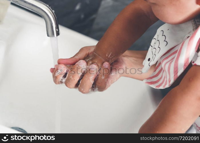 Mother wash baby hand for prevention of novel Coronavirus Disease 2019 or COVID-19 . People wash hands at bathroom sink to clean the virus infection.