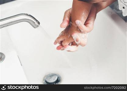 Mother wash baby hand for prevention of novel Coronavirus Disease 2019 or COVID-19 . People wash hands at bathroom sink to clean the virus infection.