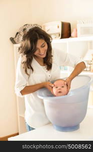 Mother washing a newborn baby in a bath tub