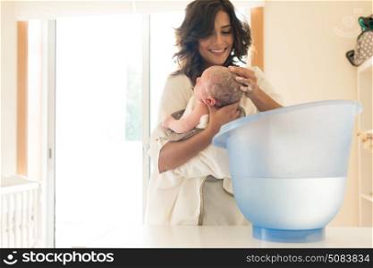 Mother washing a newborn baby in a bath tub