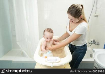 Mother washing her baby son in bath