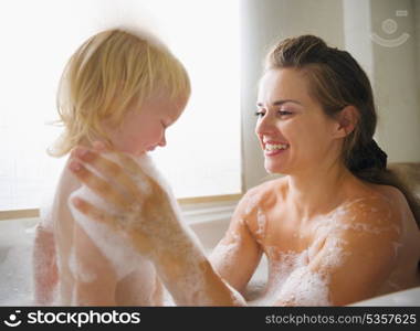 Mother washing with baby in bathtub