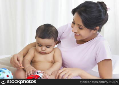 Mother watching baby play with toy cars