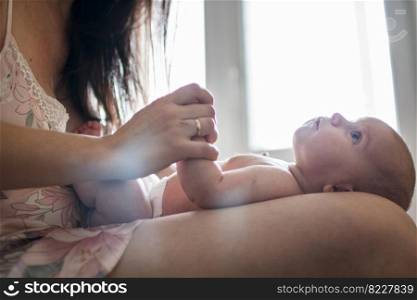 mother with a baby on a bed by the window