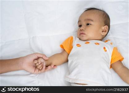 mother with baby holding hand on white mattress
