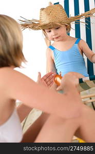 Mother with child apply suntan lotion on beach