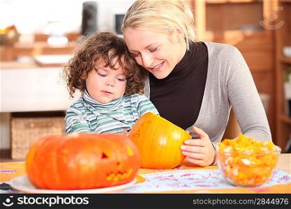 Mother with child decorating pumpkin