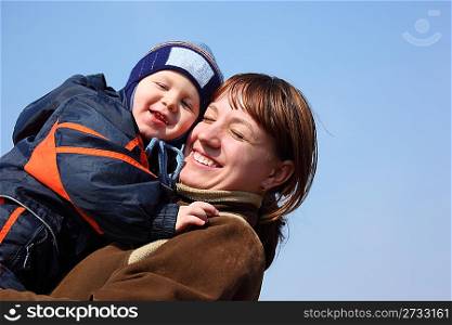 Mother with child on hands on spring sky background