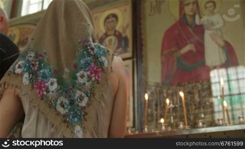 Mother with child praying before icon in Orthodox Church