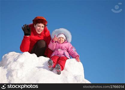 mother with child sit on snow hill