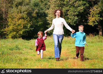Mother with children run in wood, front view