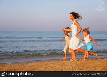 Mother with children running on edge of sea