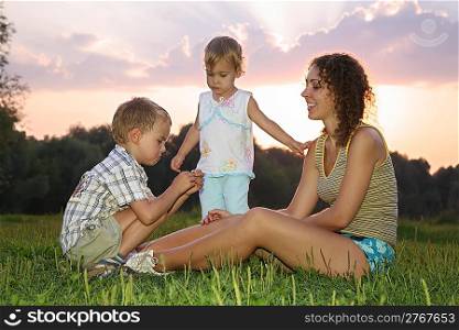 mother with children sits on the grass