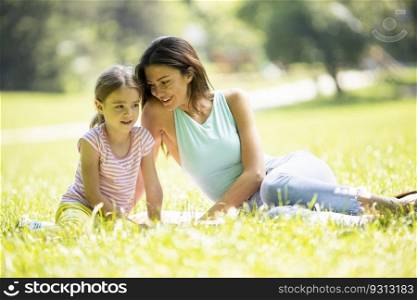 Mother with cute litt≤daughter having fun on the grass at the park