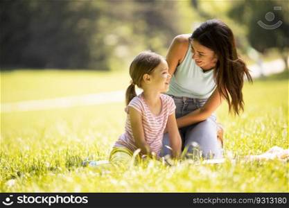 Mother with cute little daughter having fun on the grass at the park