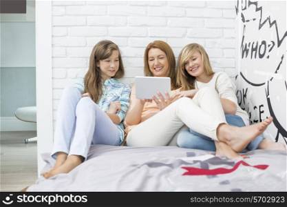 Mother with daughters using tablet PC in bedroom