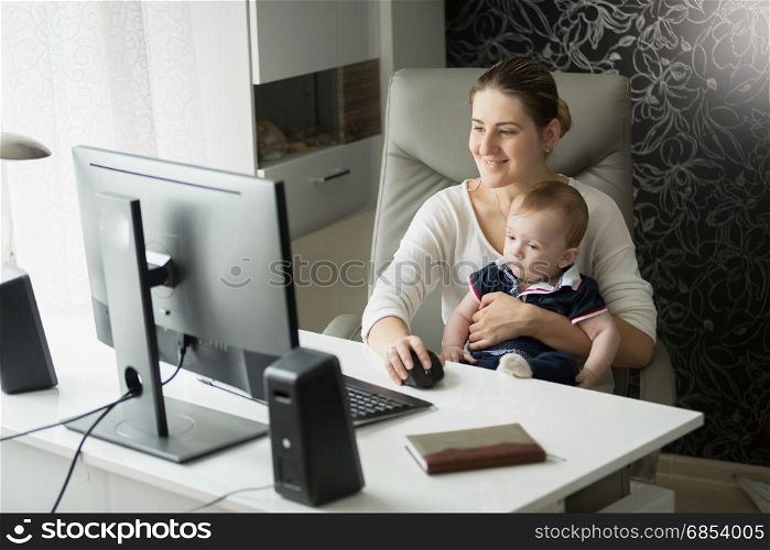Mother with her baby son in office using computer