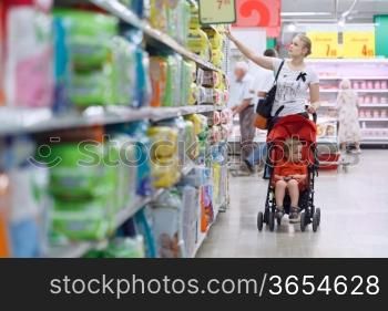Mother with her boy in baby carriage in the supermarket