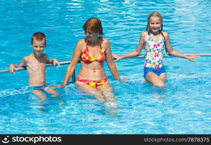 Mother with her children in the summer outdoor pool.