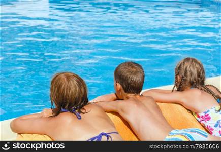 Mother with her children to bask in the sun near swimming pool