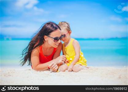 Mother with her cute daughter on summer beach vacation. Beautiful mother and daughter at the beach enjoying summer vacation