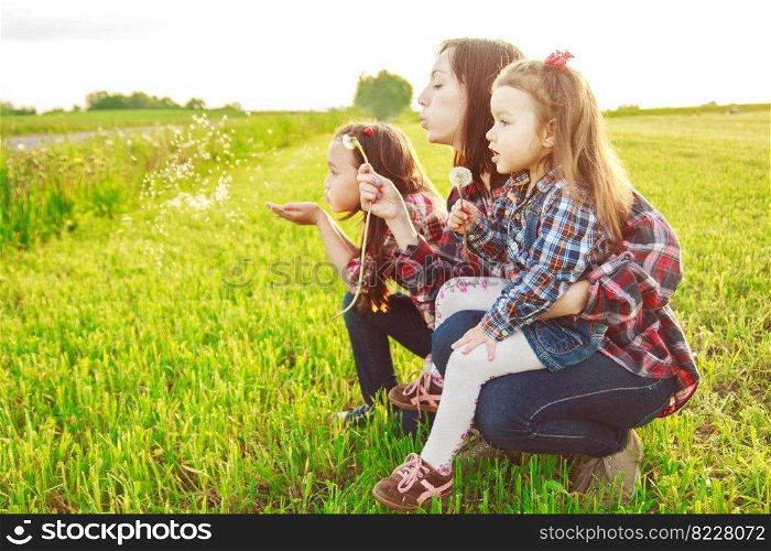 mother with her daughter in the field blowing a dendelion