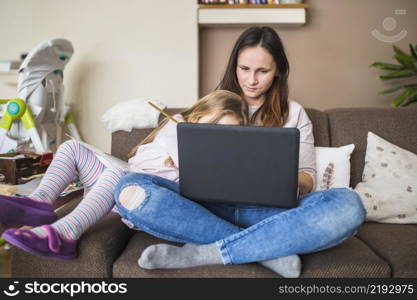 mother with her daughter sitting sofa using laptop