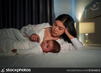 mother with her infant baby on a bed at night