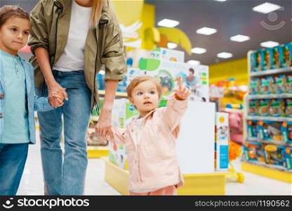 Mother with her little children in kids store. Mom with daughter and son together choosing toys in supermarket, family shopping. Mother with her little children in kids store