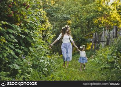 Mother with her little daughter walking in the garden.. Family walk with the children on the summer garden 4786.