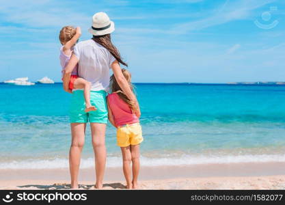 Mother with her little daughters on the beach. Beautiful mother and daughter on the beach