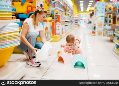 Mother with her little girl choosing baby potty in kids store. Mom and child in supermarket together, family shopping. Mother with girl choosing baby potty in kids store