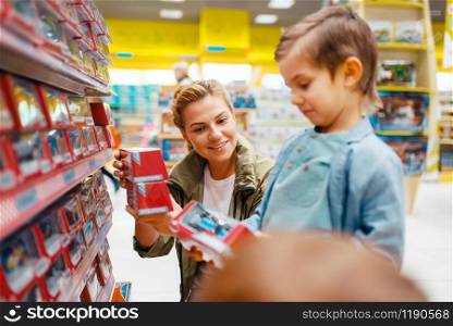 Mother with her little son in kids store. Mom and child together choosing toys in supermarket, family shopping