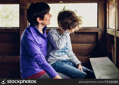 Mother with her seven year old daughter laughing in a cabin in the countryside. Lifestyle concept.. Mother with her seven year old daughter laughing in a cabin in the countryside
