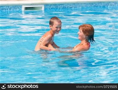 Mother with her son in the summer outdoor pool.