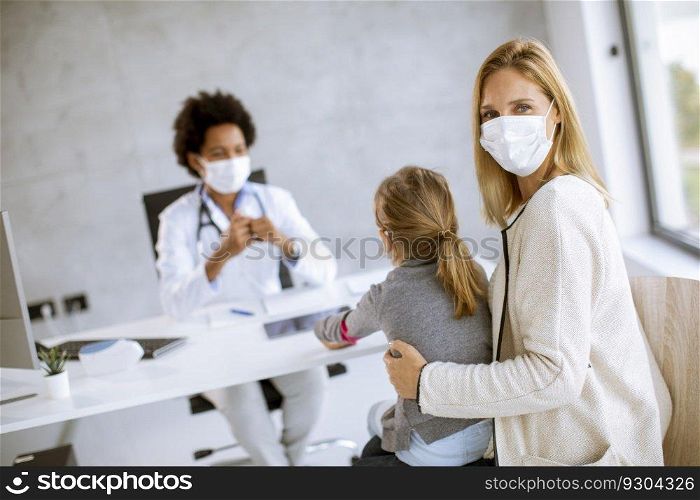 Mother with his litt≤daughter at the pediatrician examination by African american fema≤doctor