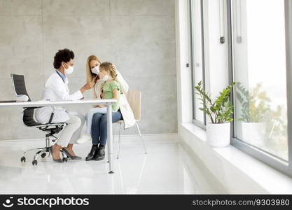 Mother with his little daughter at the pediatrician examination and having PCR diagnostic test by African american female doctor