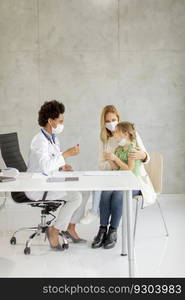 Mother with his little daughter at the pediatrician examination and having PCR diagnostic test by African american female doctor