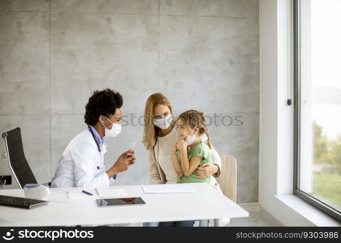 Mother with his little daughter at the pediatrician examination by African american female doctor