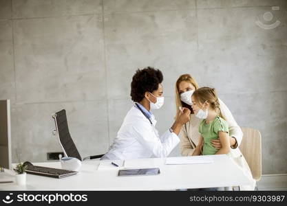 Mother with his little daughter at the pediatrician examination by African american female doctor