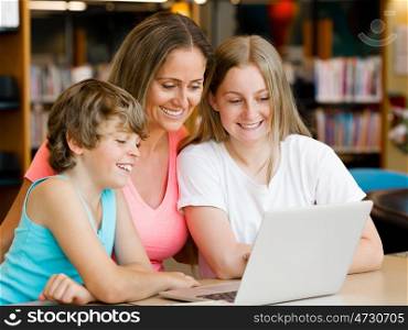 Mother with kids in library with notebook. Mother with kids in library