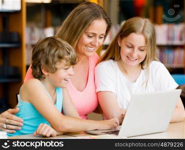Mother with kids in library with notebook. Mother with kids in library