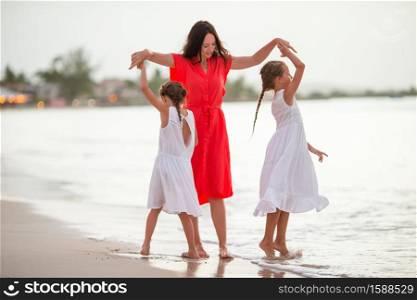 Mother with kids on the beach dance and have fun. Family vacation. Happy beautiful family on a tropical beach vacation