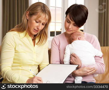 Mother With Newborn Baby Talking With Health Visitor At Home