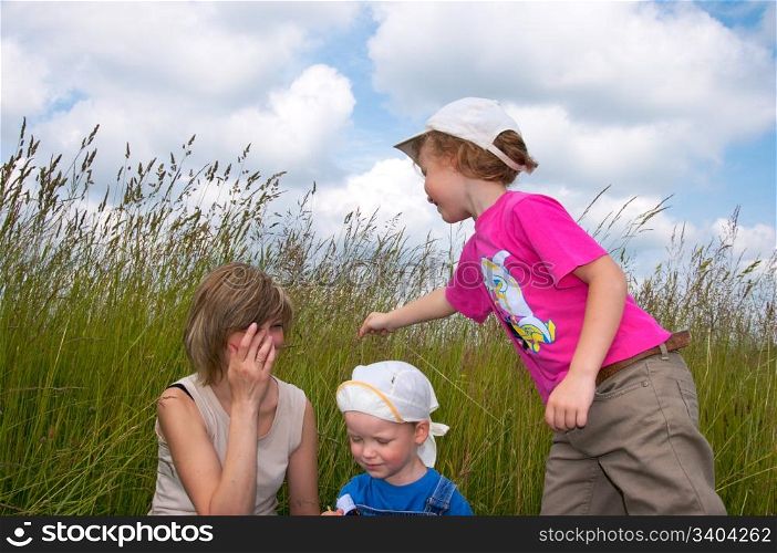 Mother with small children play in tallgrass on meadow