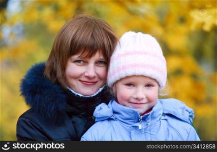 Mother with small daughter in golden autumn city park