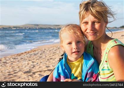 mother with small daughter on sandy sea coast