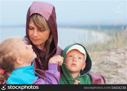 mother with small girl and boy on evening prairie near sea coast