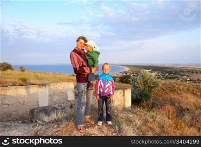 mother with small girl and boy on evening prairie near sea coast